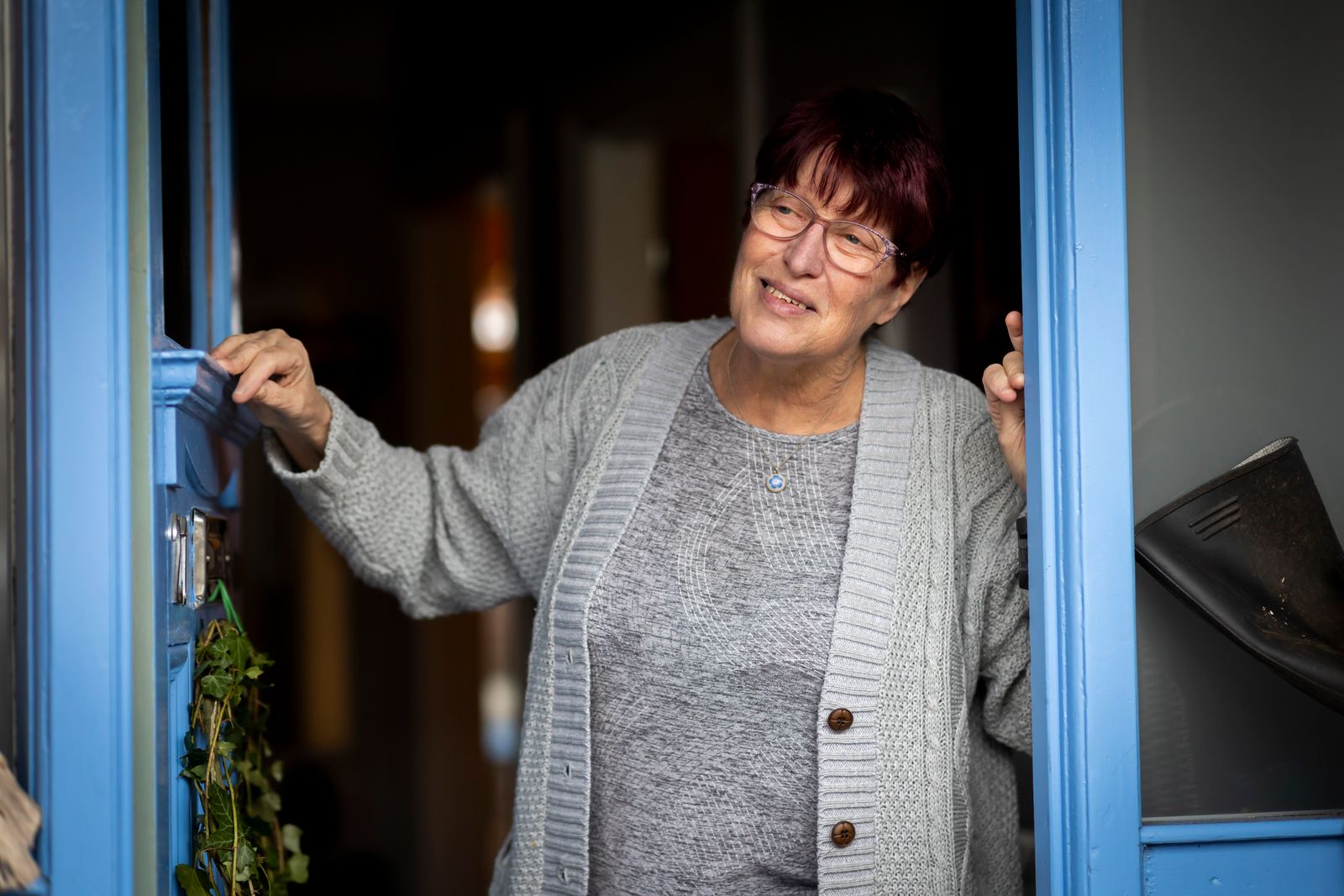 Older woman smiling warmly in the doorway of her home